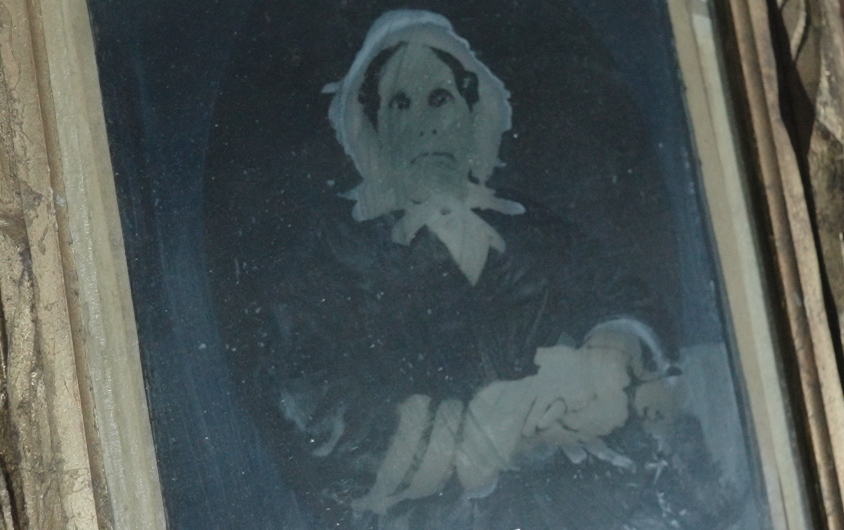 Historic photographic portrait of a bonneted woman holding a baby, displayed in relation to Mackay Mansion