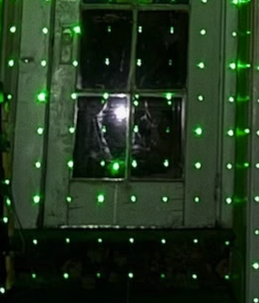 Green laser grid illuminating glass panels with a bright silhouette-like shape