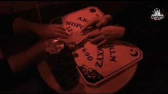 Hands around a Ouija board during a LiveSciFi paranormal investigation