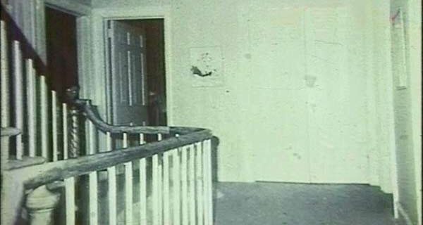 Archival photograph known as the Amityville ghost boy, a childlike figure near the staircase