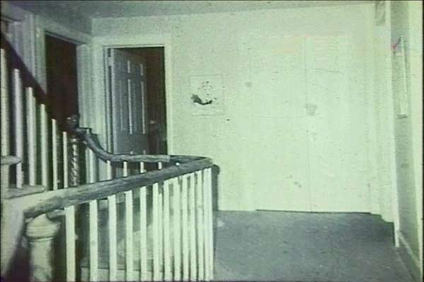 Archival Amityville ghost boy photograph showing a figure near an interior staircase, interpretation disputed